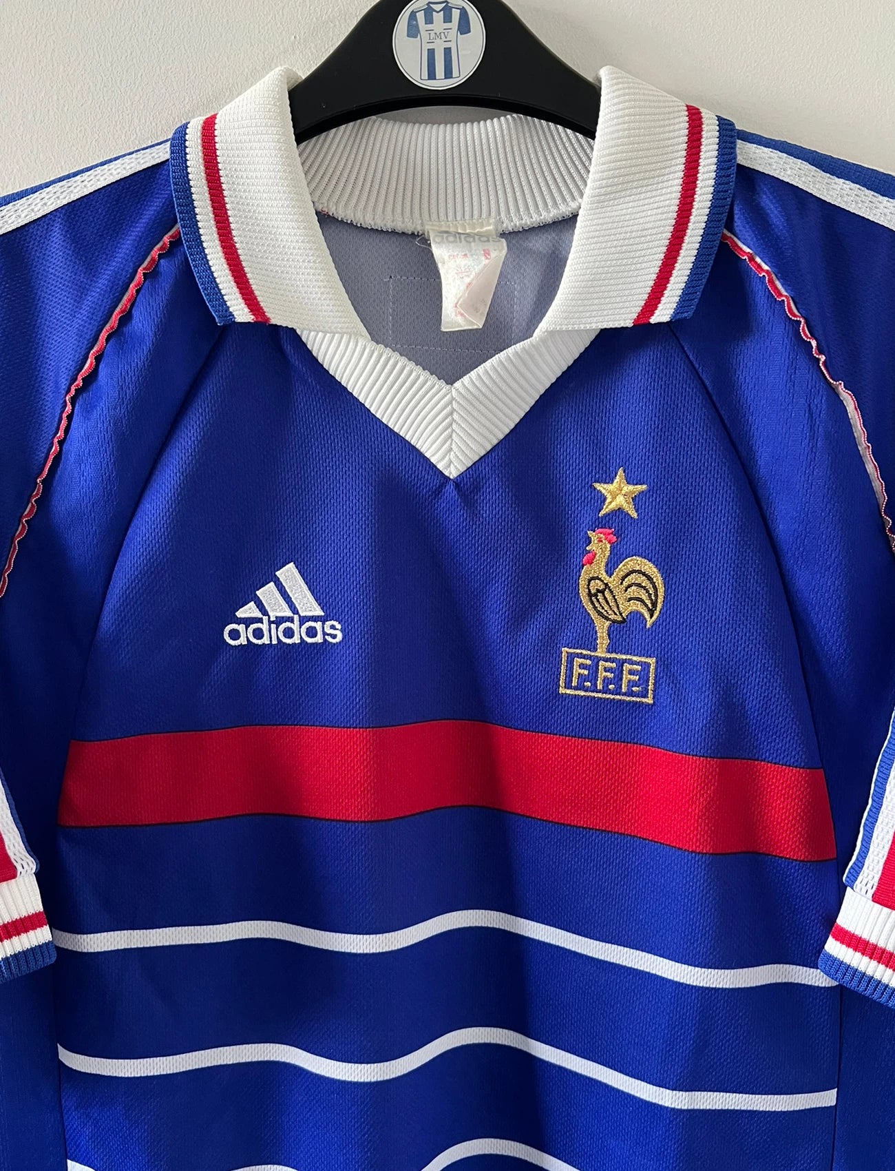 Maillot de foot vintage domicile bleu blanc et rouge de l'équipe de france 1998. On peut retrouver l'équipementier Adidas. Le maillot est floqué du numéro 10 Zinedine Zidane. Il s'agit d'un maillot authentique d'époque.