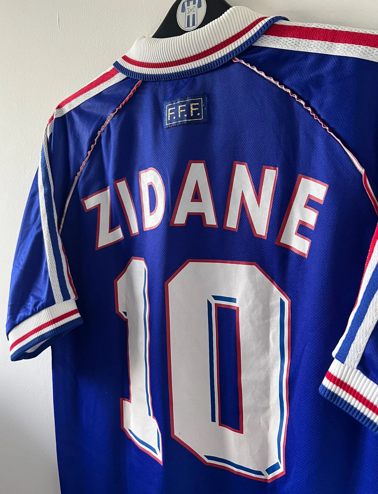 Maillot de foot vintage domicile bleu blanc et rouge de l'équipe de france 1998. On peut retrouver l'équipementier Adidas. Le maillot est floqué du numéro 10 Zinedine Zidane. Il s'agit d'un maillot authentique d'époque.