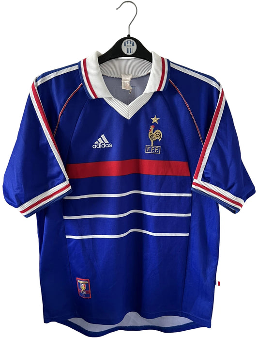 Maillot de foot vintage domicile bleu blanc et rouge de l'équipe de france 1998. On peut retrouver l'équipementier Adidas. Le maillot est floqué du numéro 10 Zinedine Zidane. Il s'agit d'un maillot authentique d'époque.