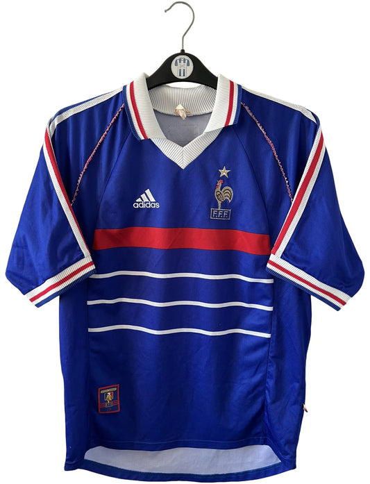Maillot de foot vintage domicile bleu de l'Equipe de France 1998. On peut retrouver l'équipementier Adidas. Le maillot est floqué du numéro 10 Zinedine Zidane. Il s'agit d'un maillot authentique d'époque.