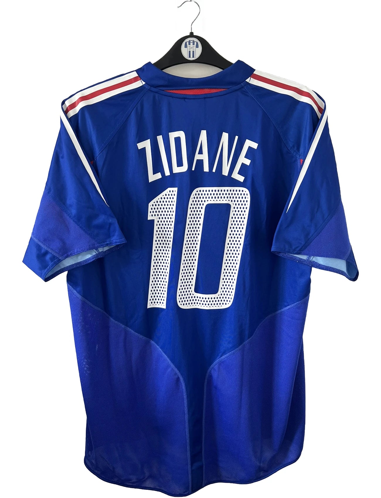 Maillot de foot vintage domicile de l'équipe de france 2004/2006. On peut retrouver l'équipementier adidas. Le maillot est floqué du numéro 10 Zinedine Zidane. Il s'agit d'un maillot authentique d'époque comportant l'étiquette 600222.