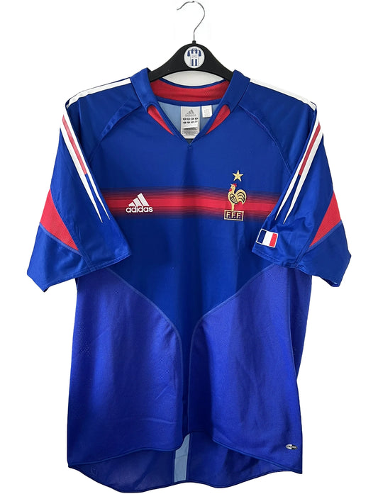 Maillot de foot vintage domicile de l'équipe de france 2004/2006. On peut retrouver l'équipementier adidas. Le maillot est floqué du numéro 10 Zinedine Zidane. Il s'agit d'un maillot authentique d'époque comportant l'étiquette 600222.