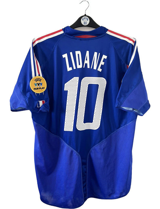 Maillot de foot vintage domicile bleu blanc et rouge de l'équipe de france 2004. On peut retrouver l'équipementier adidas. Il s'agit d'un maillot authentique d'époque comportant le numéro 641768