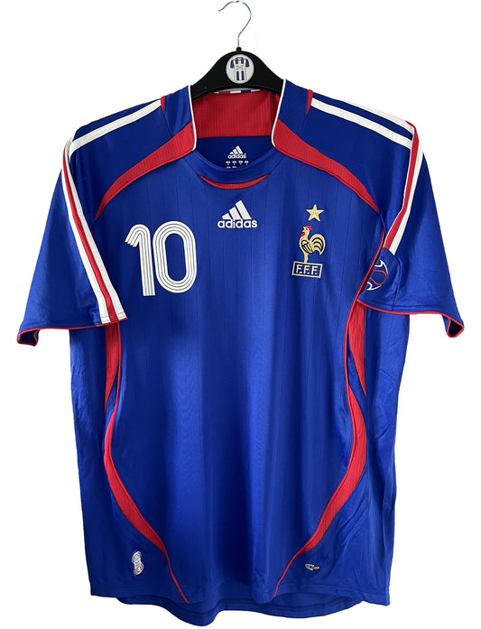 Maillot de foot vintage domicile bleu de l'équipe de france 2006. On peut retrouver l'équipementier adidas. Le maillot est floqué du numéro 10 Zinedine Zidane. Il s'agit d'un maillot authentique comportant l'étiquette 740126.