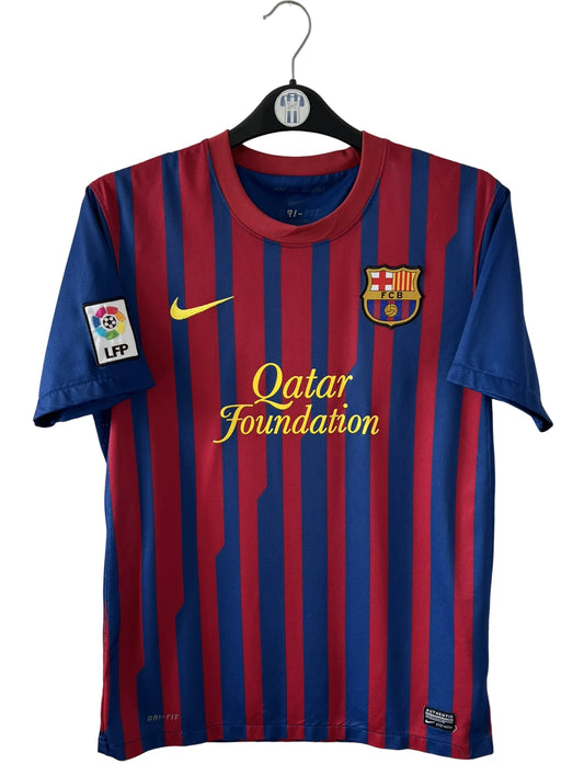 Maillot de foot vintage domicile rouge et bleu du FC Barcelone 2011/2012. On peut retrouver l'équipementier Nike et le sponsor Qatar Foundation. Le maillot est floqué du numéro 6 Xavi. Il s'agit d'un maillot authentique d'époque.