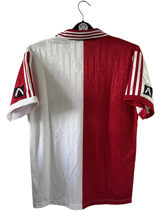 Maillot de foot vintage domicile rouge et blanc de Feyenoord de la saison 1996/1997. On peut retrouver l'équipementier Adidas et le sponsor Stad Rotterdam Verzekeringer. Il s'agit d'un maillot authentique d'époque.