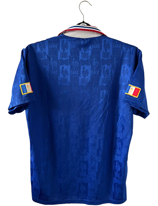 Maillot de foot vintage domicile bleu de l'Equipe de France 1996. On peut retrouver l'équipementier Adidas. Il s'agit d'un maillot authentique d'époque.