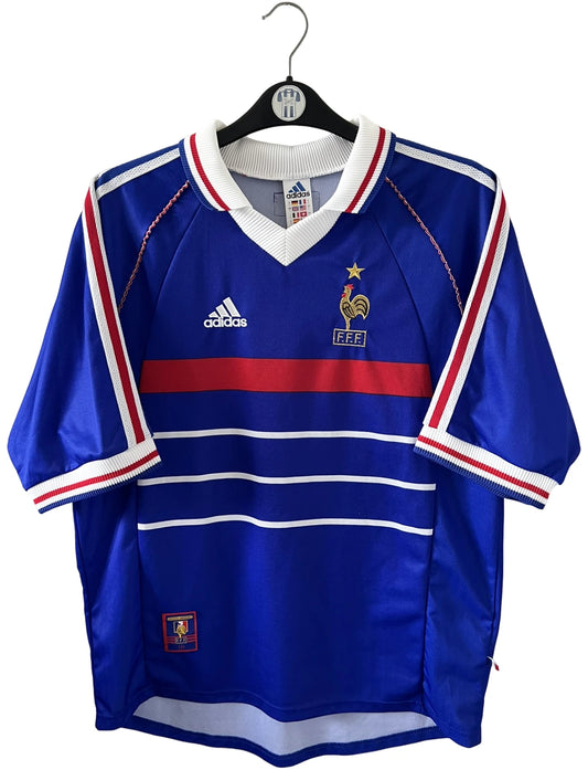 Maillot foot vintage domicile equipe de france 1998 bleu blanc et rouge. On peut retrouver l'équipementier adidas. Le maillot est floqué du numéro 10 Zinedine Zidane. Il s'agit d'un maillot authentique d'époque vendu avec son short d'époque.
