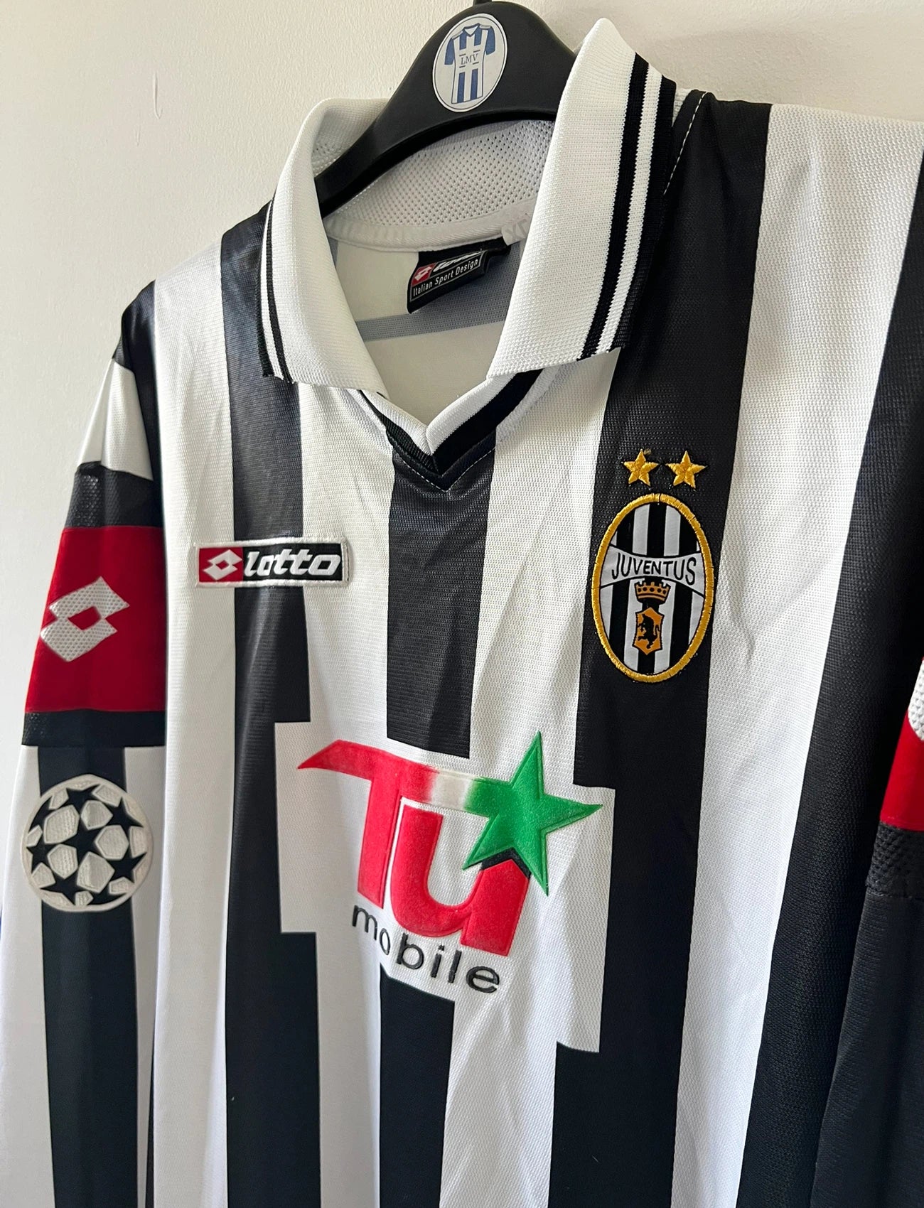 Maillot de foot vintage domicile noir et blanc de la juventus de la saison 2001/002. On peut retrouver l'équipementier Lotto et le sponsor TU Mobile. Il s'agit d'un maillot authentique d'époque, issu du stock pro de la juventus en version Ligue des Champions