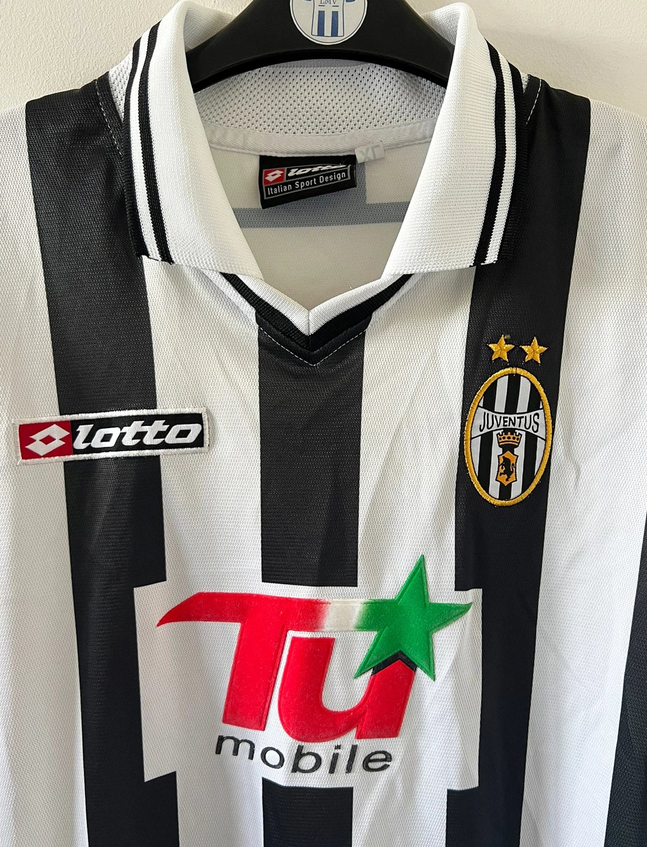 Maillot de foot vintage domicile noir et blanc de la juventus de la saison 2001/002. On peut retrouver l'équipementier Lotto et le sponsor TU Mobile. Il s'agit d'un maillot authentique d'époque, issu du stock pro de la juventus en version Ligue des Champions