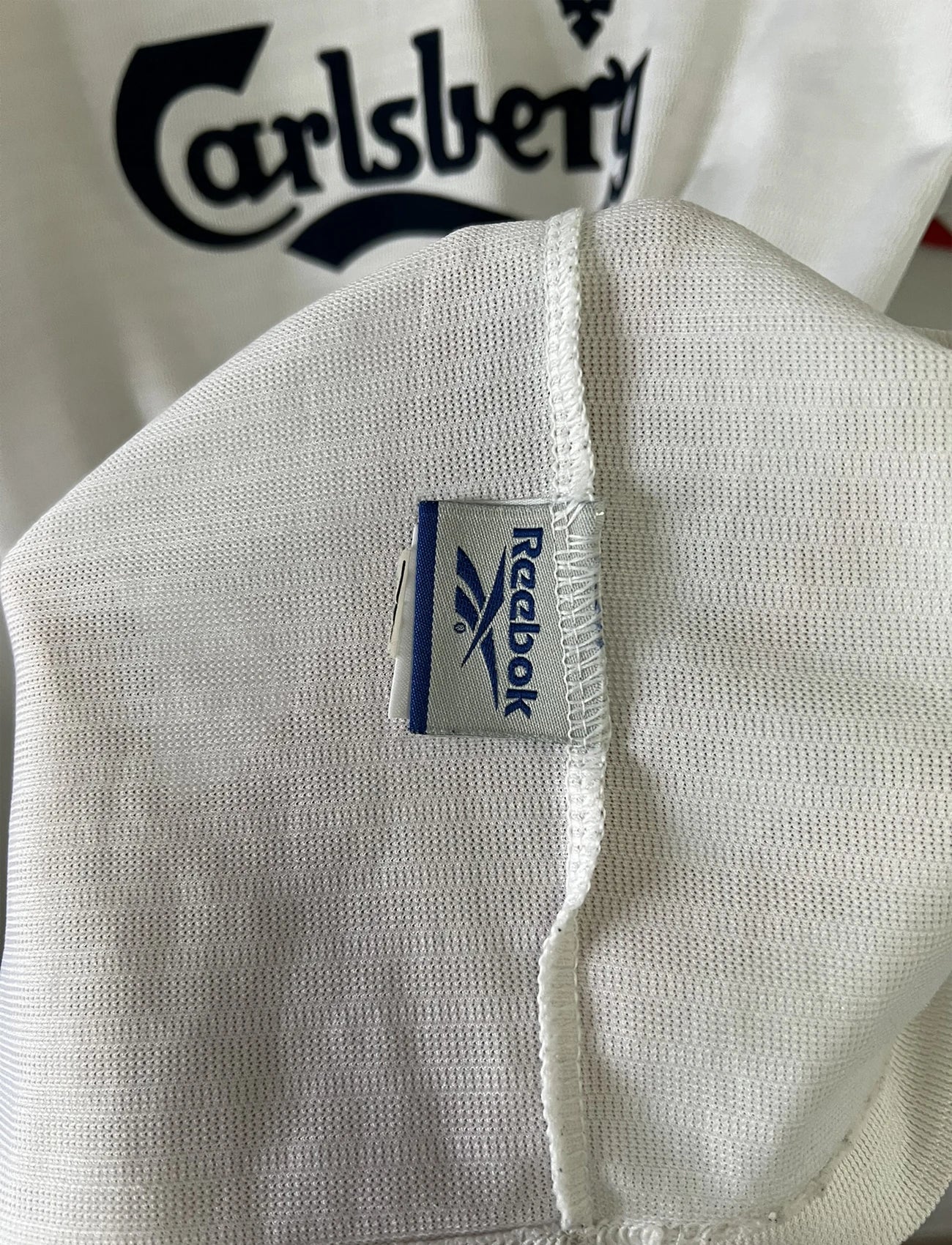 Maillot foot vintage extérieur liverpool blanc et rouge de la saison 1999/2000. On peut retrourver l'équipementier reebok et le sponsor carlsberg. Le maillot est floqué du numéro 10 Michael Owen. Il s'agit d'un maillot authentique d'époque.
