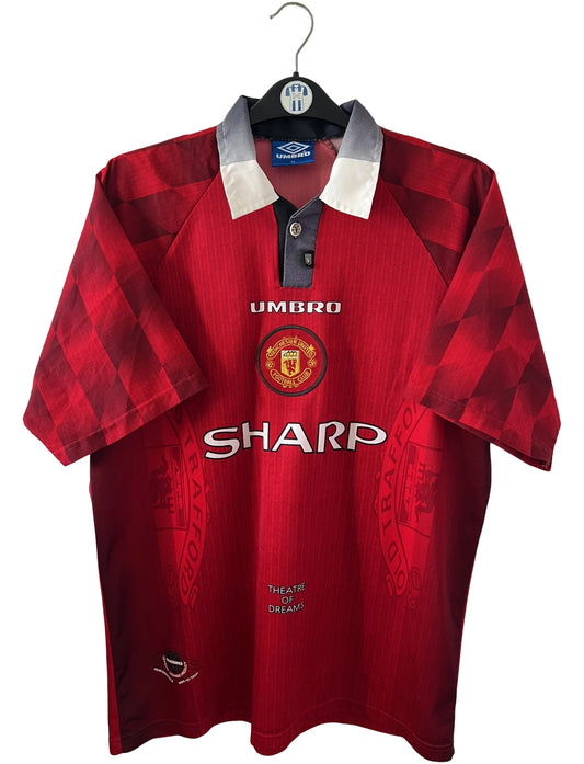 Maillot de foot vintage domicile rouge de Manchester United 1996/1998. On peut retrouver l'équipementier Umbro et le sponsor Sharp. Le maillot est floqué du numéro 7 Eric Cantona. Il s'agit d'un maillot authentique d'époque.