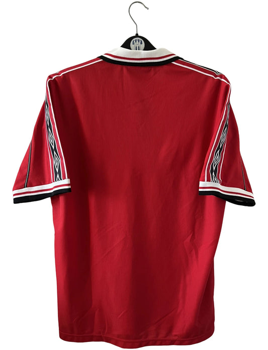 Maillot de foot vintage domicile rouge de Manchester United saison 1998/2000. On peut retrouver l'équipementier Umbro et le sponsor Sharp. Il s'agit d'un maillot authentique d'époque.