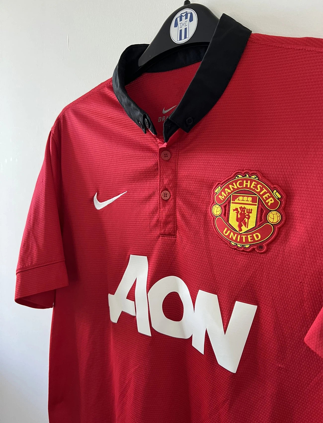 Maillot de foot vintage domicile rouge et noir de manchester united de la saison 2013/14. On peut retrouver l'équipementier nike et le sponsor Aon. Il s'agit d'un maillot authentique comportant les numéros 532837-624