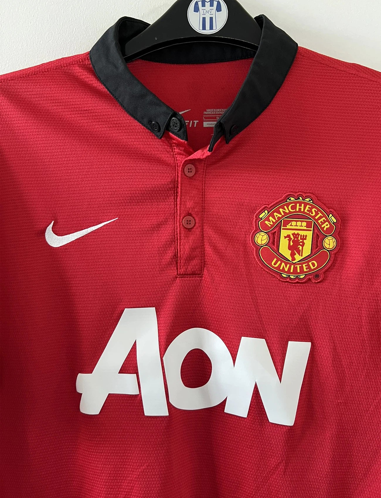 Maillot de foot vintage domicile rouge et noir de manchester united de la saison 2013/14. On peut retrouver l'équipementier nike et le sponsor Aon. Il s'agit d'un maillot authentique comportant les numéros 532837-624