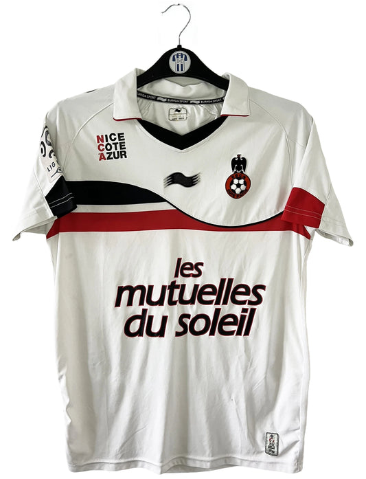 Maillot de foot vintage extérieur blanc de l'OGC Nice porté par Fabian Monzon lors de la saison 2011/2012. On peut retrouver l'équipementier Burrda Sport et le sponsor Mutuelle du Soleil. Le maillot est floqué du numéro 18 Fabian Monzon. Il s'agit d'un maillot authentique d'époque.