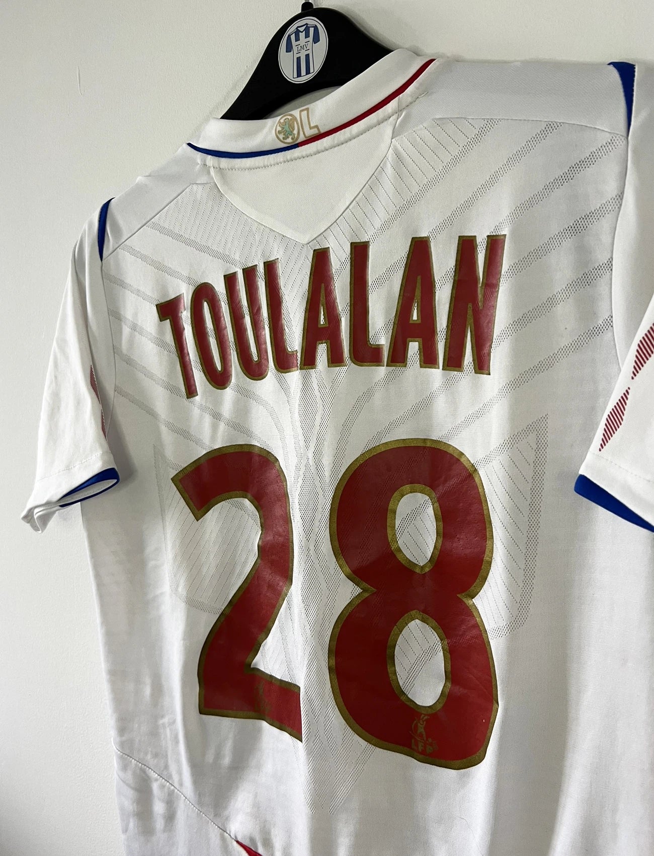 Maillot de foot vintage domicile blanc de l'OL de la saison 2008/2009. On peut retrouver l'équipementier umbro et le sponsor novotel. Le maillot est floqué du numéro 28 Jérémy Toulalan. Il s'agit d'un maillot authentique d'époque.