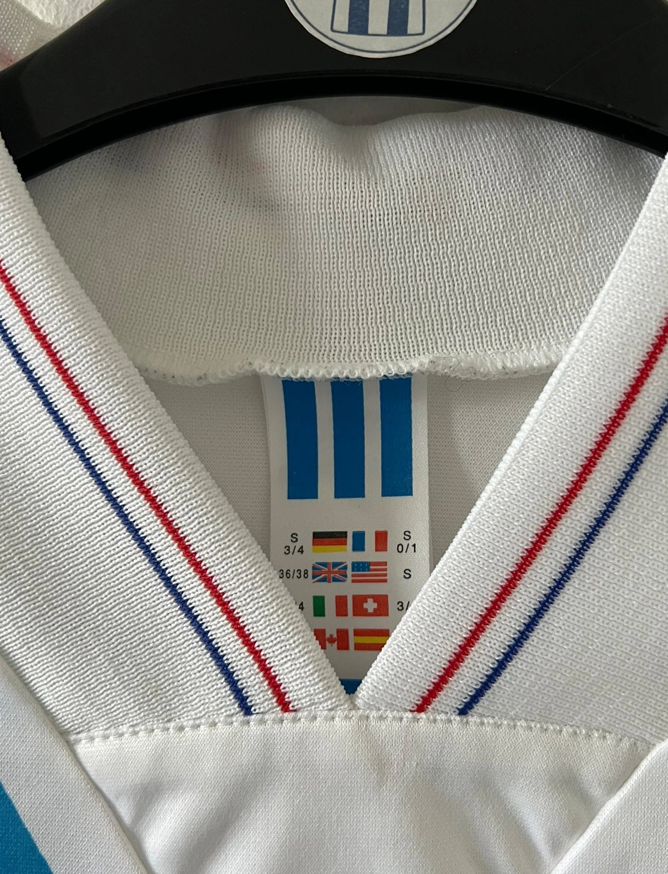 Maillot de foot vintage domicile blanc et bleu de la saison 1991/1992. On peut retrouver l'équipementier Adidas et le sponsor Panasonic. Il s'agit d'un maillot authentique d'époque.