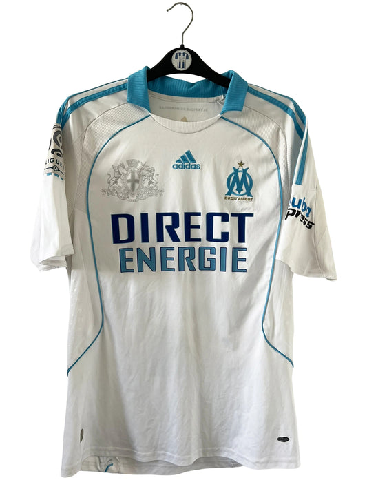 Maillot de foot vintage domicile blanc de l'OM de la saison 2008/2009. On peut retrouver l'équipementier Adidas et le sponsor Direct Energie. Le maillot est floqué du numéro 11 Mamadou Niang. Il s'agit d'un maillot authentique d'époque.