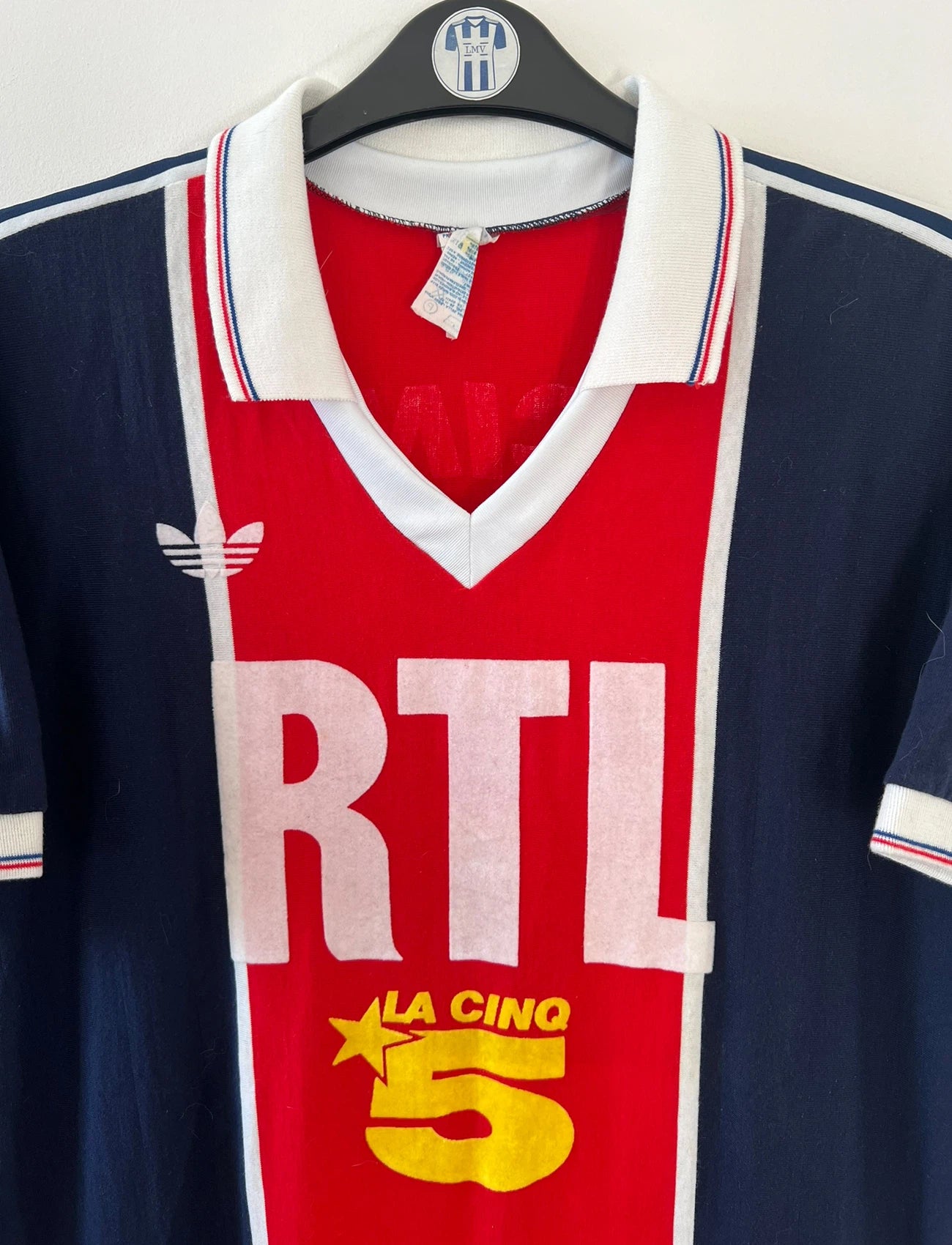 Maillot de foot vintage domicile bleu et rouge du PSG de la saison 1987/1988. On peut retrouver l'équipementier Adidas et le sponsor RTL, Canal + et La Cinq. Il s'agit d'un maillot authentique d'époque.