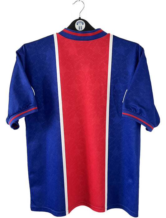 Maillot de foot vintage domicile bleu et rouge du PSG de la saison 1995/1996. On peut retrouver l'équipementier Nike et le sponsor Opel. Il s'agit d'un maillot authentique d'époque.