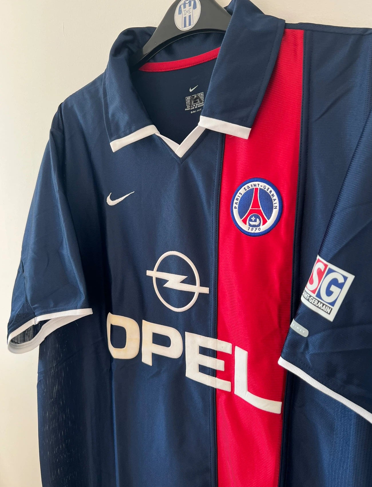 Maillot de foot vintage bleu et rouge du PSG 2001/2002. On peut retrouver l'équipementier Nike et le sponsor Opel. Il s'agit d'un maillot authentique d'époque.