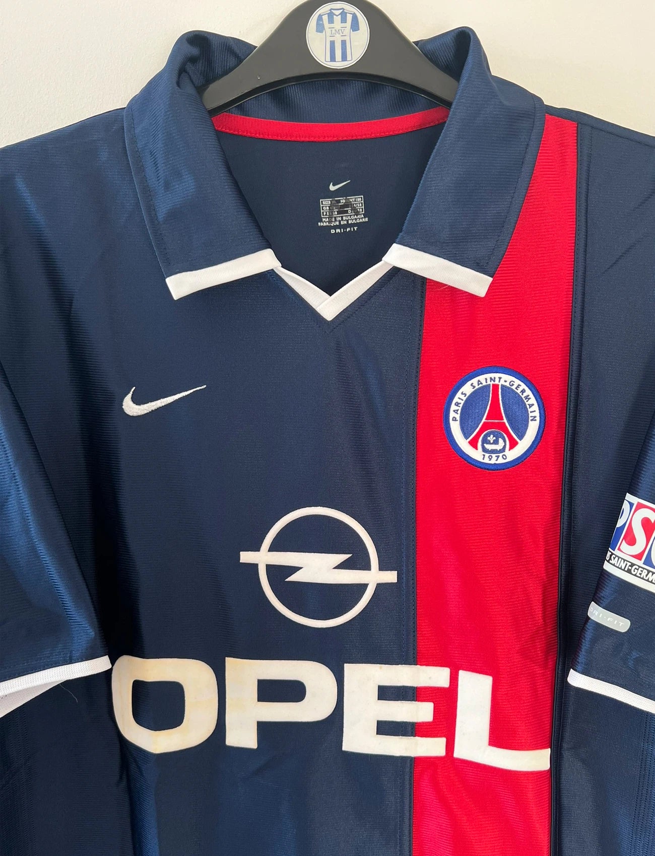 Maillot de foot vintage bleu et rouge du PSG 2001/2002. On peut retrouver l'équipementier Nike et le sponsor Opel. Il s'agit d'un maillot authentique d'époque.
