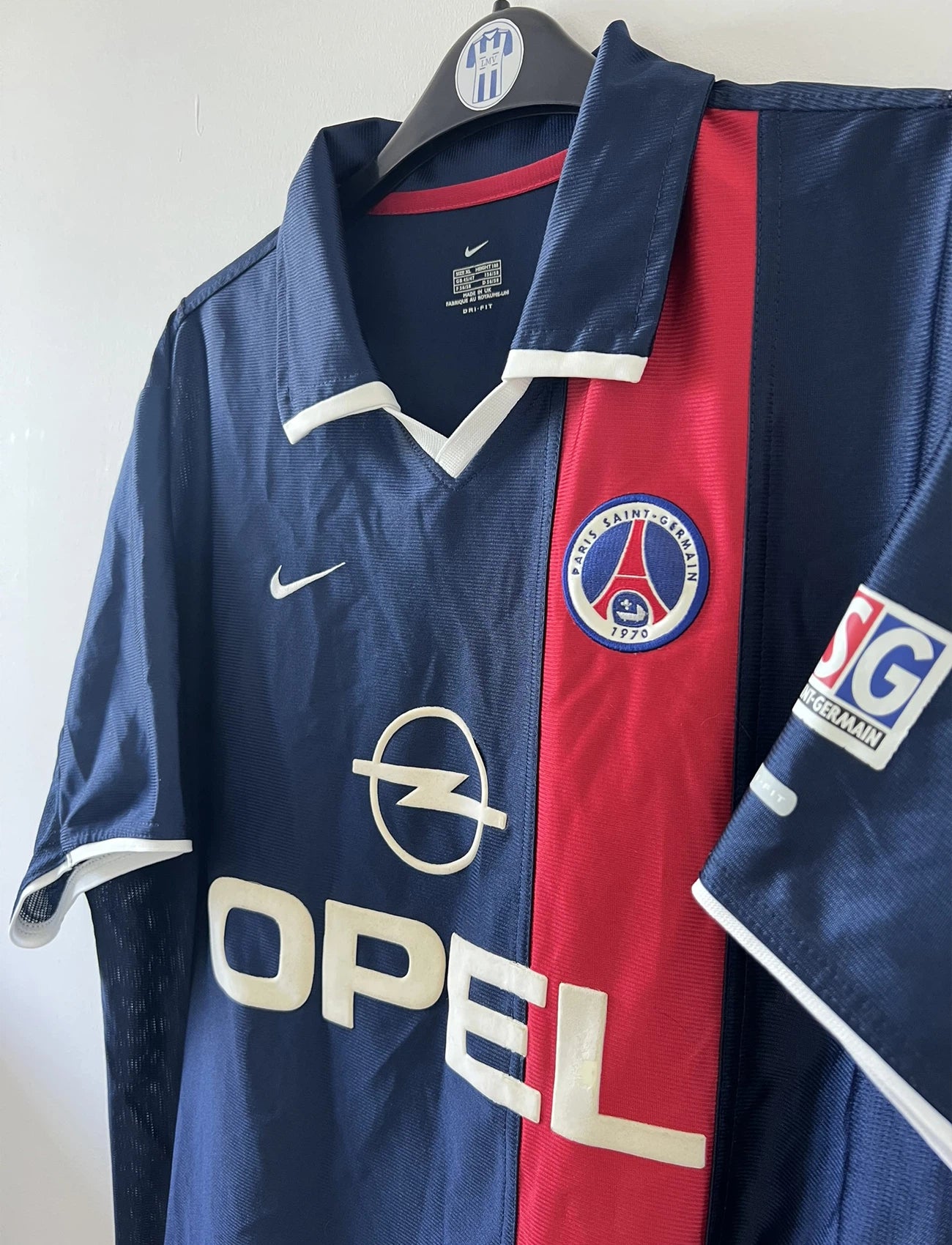 Maillot de foot vintage domicile bleu rouge et blanc du PSG de la saison 2001/2002. On peut retrouver l'équipementier nike et le sponsor Opel. Il s'agit d'un maillot authentique d'époque.