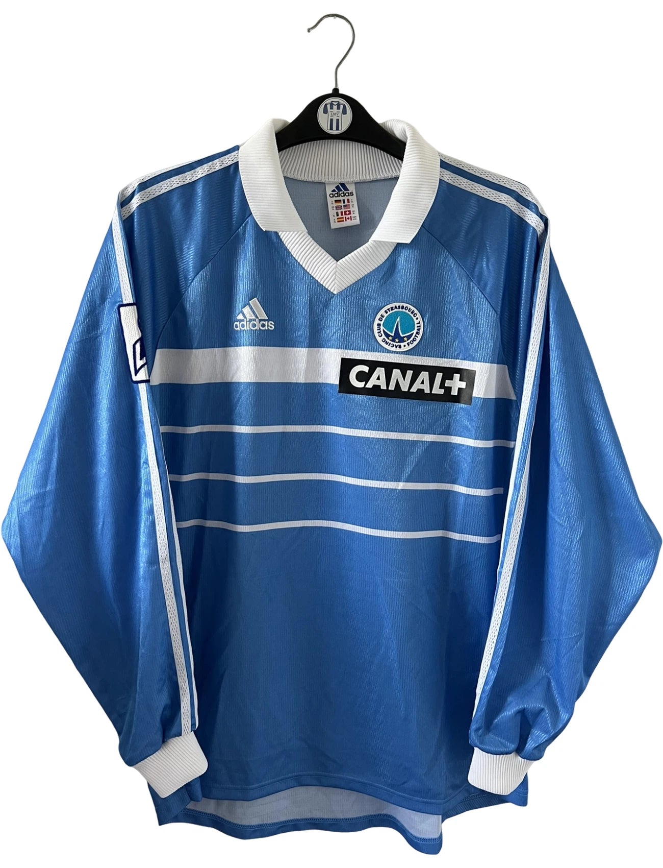Maillot de foot vintage domicile bleu de strasbourg de la saison 1999/2000. On peut retrouver l'équipementier Adidas et le sponsor Canal+. Il s'agit d'un maillot authentique d'époque, issu du stock pro du club