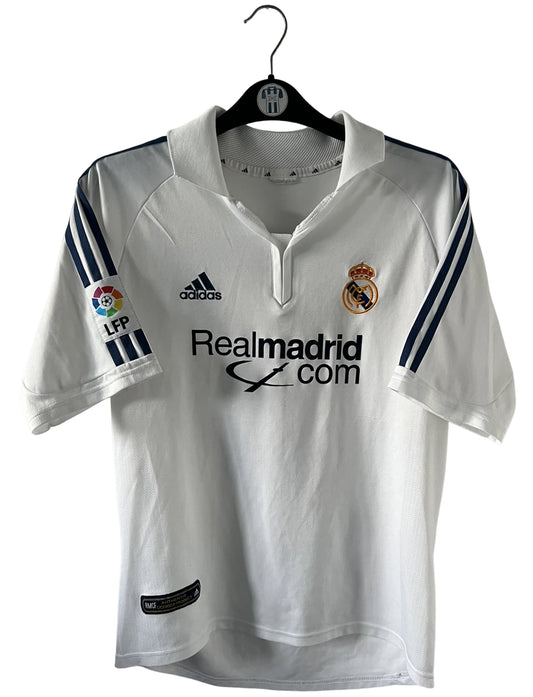 Maillot de foot vintage domicile blanc du real madrid de la saison 2001/2002. On peut retrouver l'équipementier Adidas et le sponsor Real Madrid.com. Le maillot est floqué du numéro 5 Zinedine Zidane. Il s'agit d'un maillot authentique d'époque.