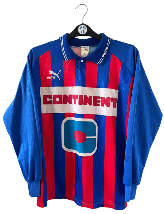 Maillot de foot vintage domicile rouge et bleu du SM Caen de la saison 1994/1995. On peut retrouver l'équipementier Puma et le sponsor Continent. Le maillot est floqué du numéro 9 Kennet Andersson. Il s'agit d'un maillot authentique d'époque.