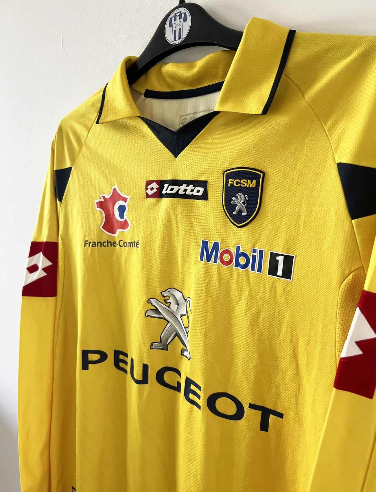 Maillot de foot vintage domicile manche longe jaune de sochaux montbéliard de la saison 2010/2011. On peut retrouver l'équipementier Lotto et le sponsor Peugeot. Le maillot est floqué du numéro 14 Marvin Martin. Il s'agit d'un maillot authentique d'époque.