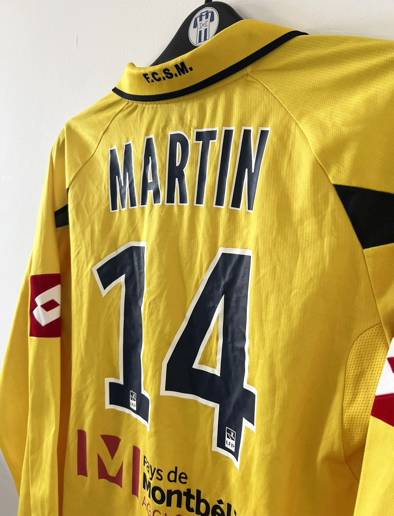 Maillot de foot vintage domicile manche longe jaune de sochaux montbéliard de la saison 2010/2011. On peut retrouver l'équipementier Lotto et le sponsor Peugeot. Le maillot est floqué du numéro 14 Marvin Martin. Il s'agit d'un maillot authentique d'époque.