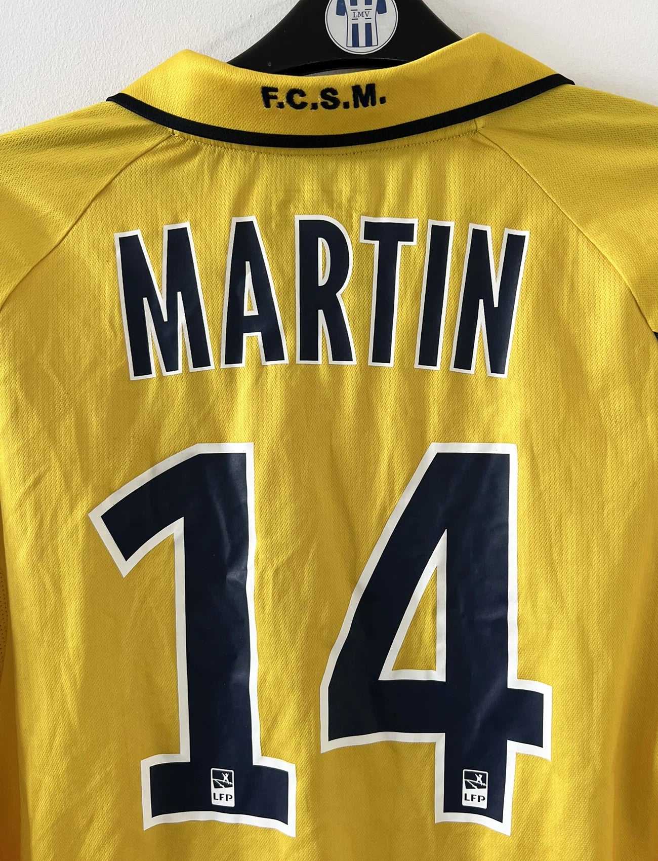 Maillot de foot vintage domicile manche longe jaune de sochaux montbéliard de la saison 2010/2011. On peut retrouver l'équipementier Lotto et le sponsor Peugeot. Le maillot est floqué du numéro 14 Marvin Martin. Il s'agit d'un maillot authentique d'époque.