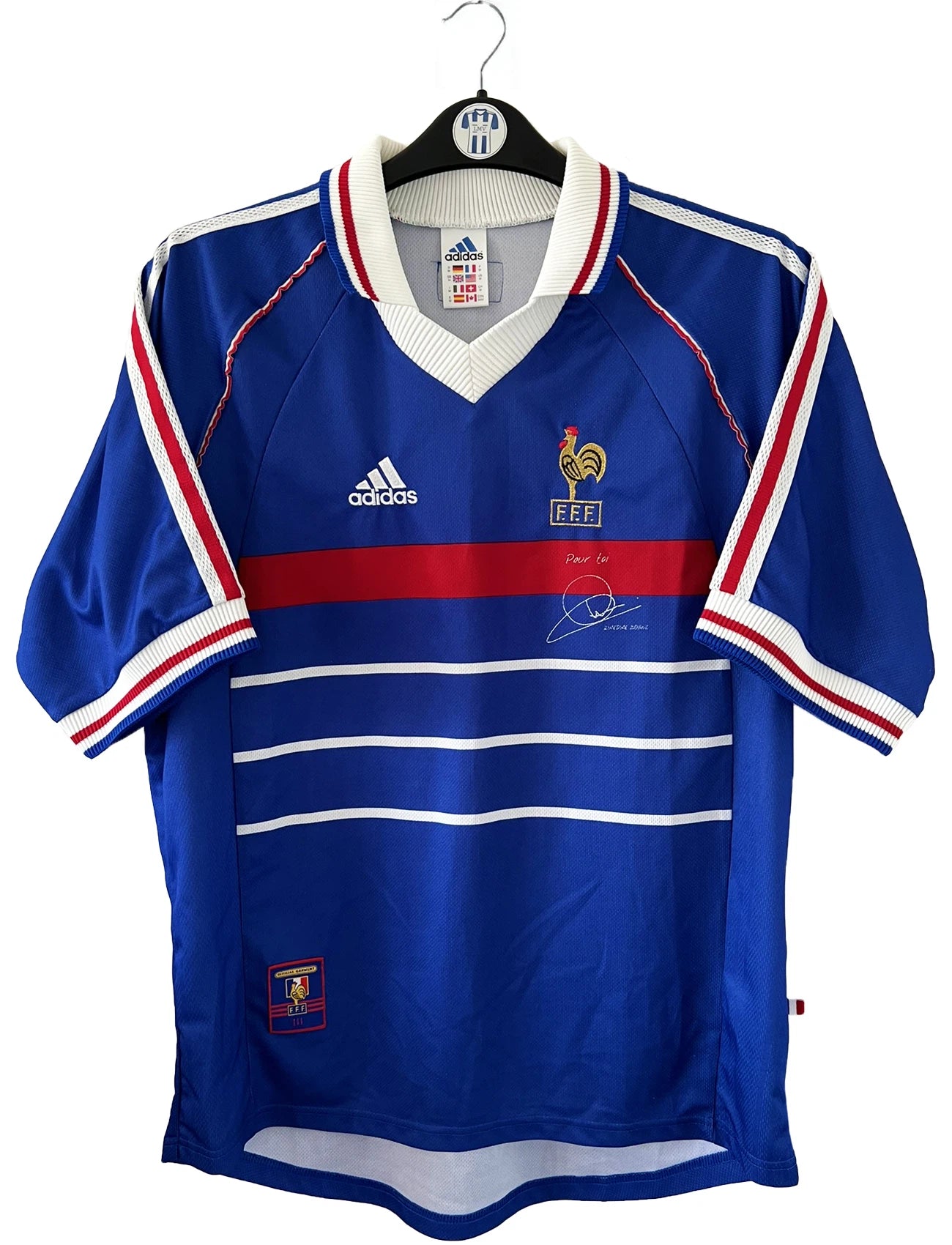 Maillot de foot vintage domicile bleu de l'Equipe de France 1998. On peut retrouver l'équipementier Adidas. Le maillot a été édité avant la finale puisqu'il ne comporte pas l'étoile. Le maillot possède également la signature et la mention "pour toi zinedine zidane". Il s'agit d'un maillot authentique d'époque.
