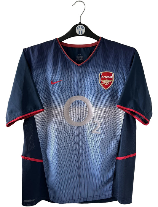 Maillot foot vintage extérieur bleu d'arsenal de la saison 2002/2003. On peut retrouver l'équipementier Nike et le sponsor O2. Le maillot est floqué du numéro 14 Thierry Henry. Il s'agit d'un maillot authentique d'époque.