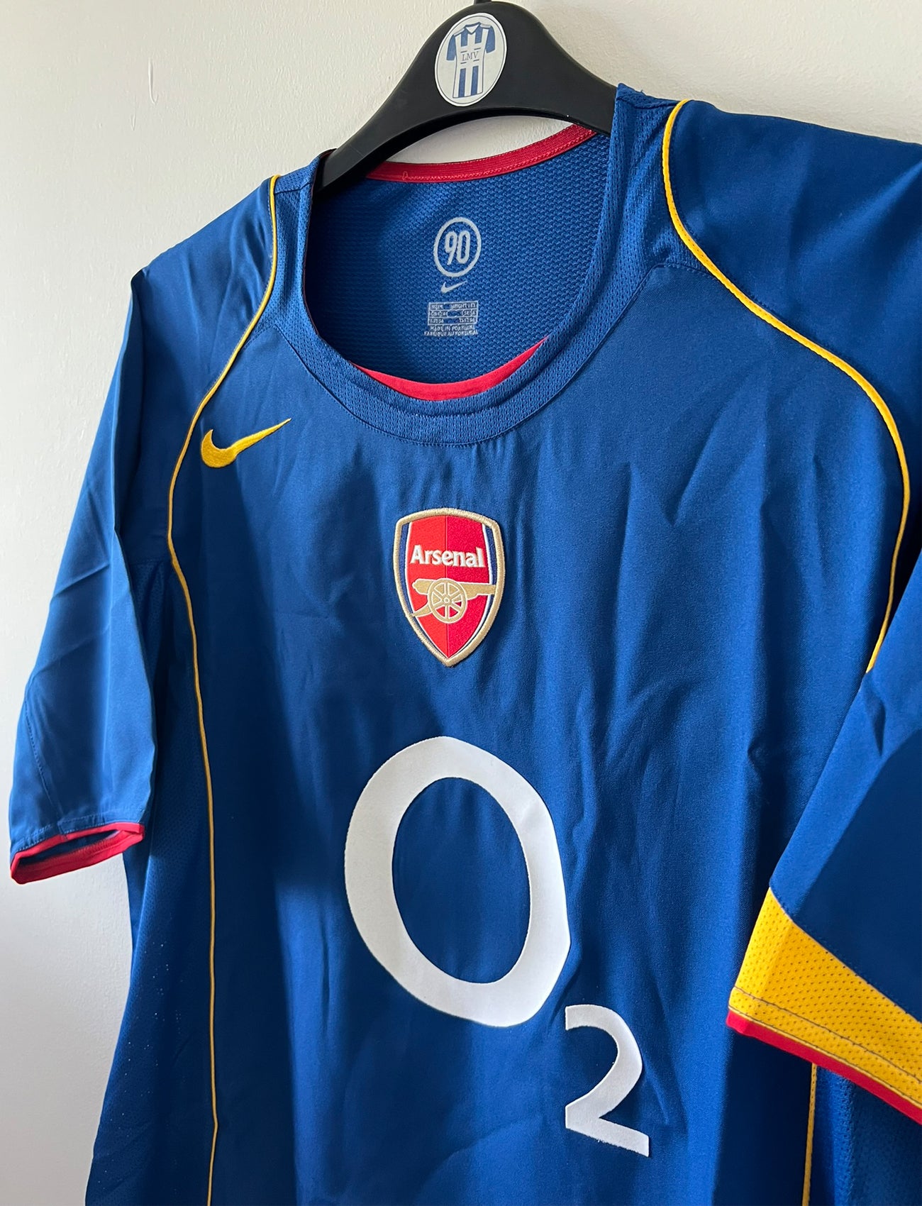 Maillot de foot vintage extérieur bleu d'Arsenal de la saison 2004/2005. On peut retrouver l'équipementier Nike et le sponsor O2. Il s'agit d'un maillot authentique d'époque.