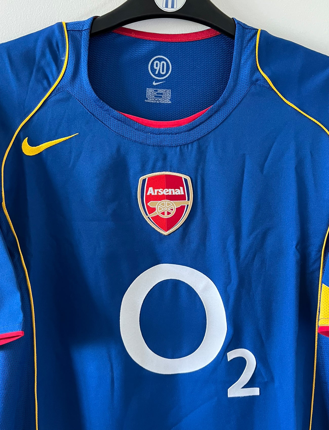 Maillot de foot vintage extérieur bleu d'Arsenal de la saison 2004/2005. On peut retrouver l'équipementier Nike et le sponsor O2. Il s'agit d'un maillot authentique d'époque.