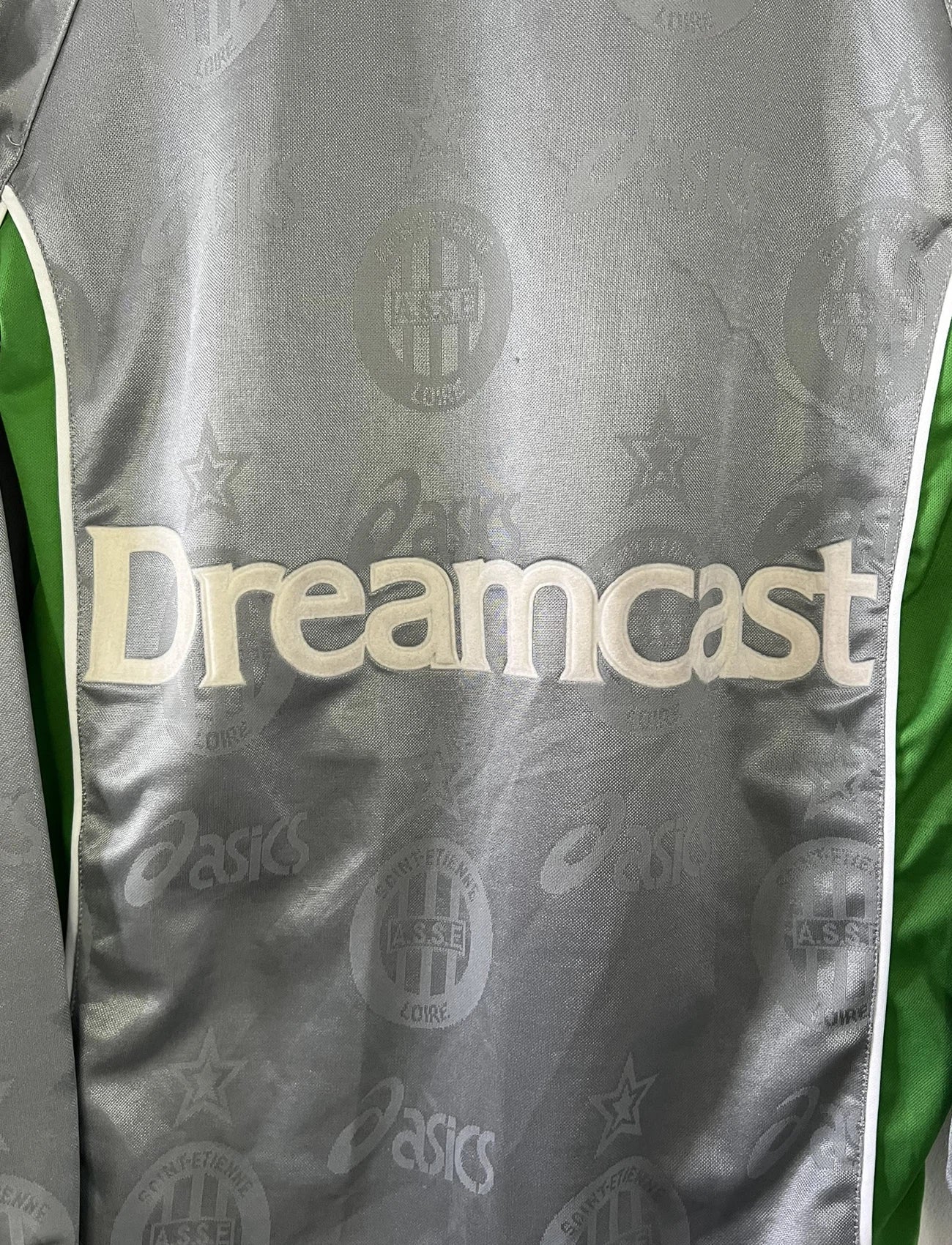 Maillot de foot vintage extérieur gris de l'AS Saint Etienne de la saison 1999/2000. On peut retrouver l'équipementier Asics et les sponsor, Sega, Géant Casino, Dreamcast. Il s'agit d'un maillot authentique d'époque.