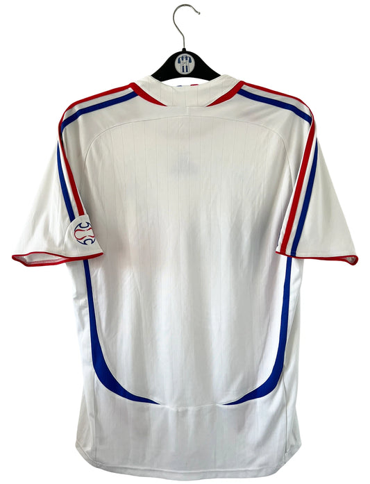 Maillot de foot vintage extérieur blanc de l'équipe de France 2006. On peut retrouver l'équipementier Adidas. Il s'agit d'un maillot authentique d'époque comportant l'étiquette 740125