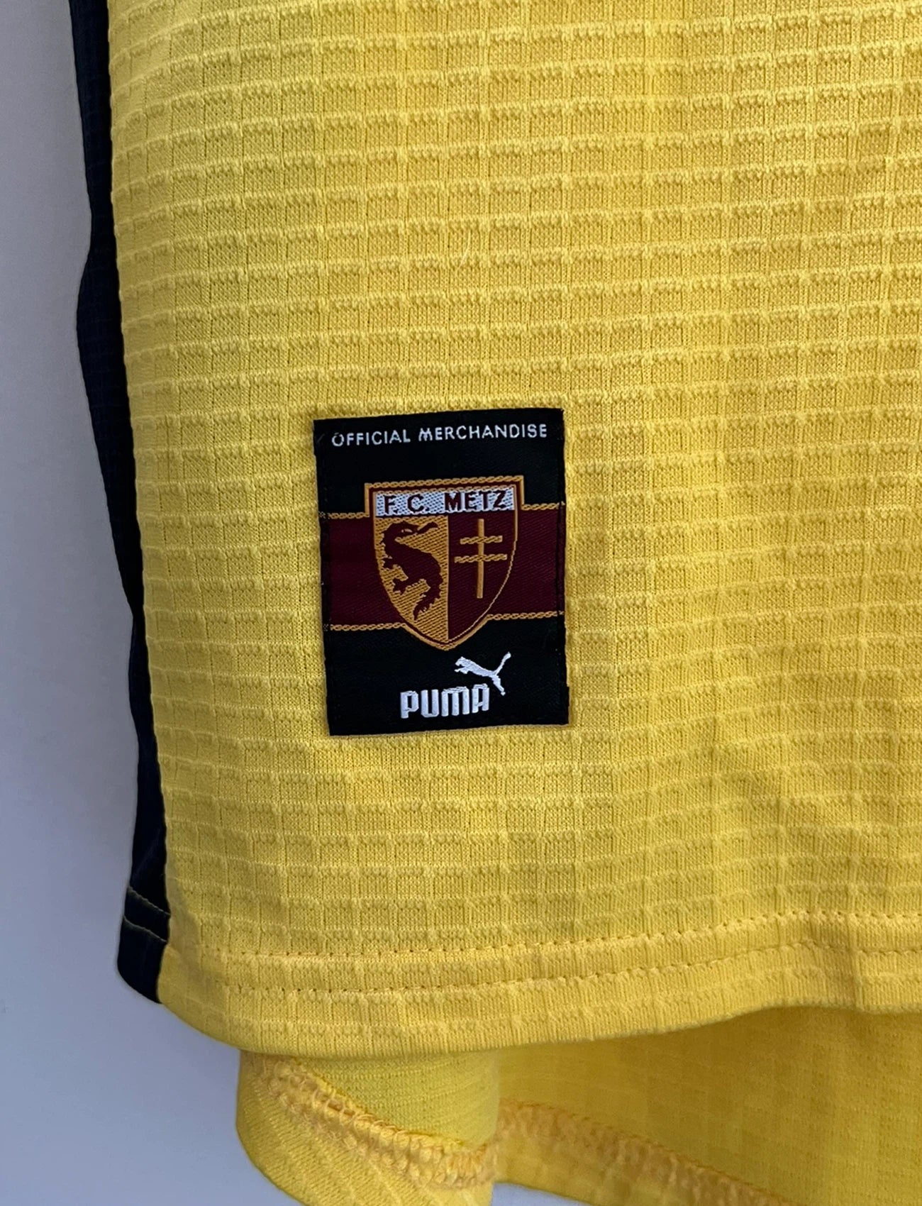 Maillot de foot vintage extérieur jaune du FC Metz de la saison 1999/2000. On peut retrouver l'équipementier Puma. Il s'agit d'un maillot authentique d'époque, issu du stock pro du FC Metz.