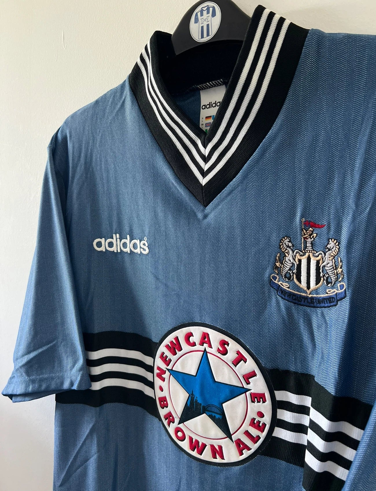 Maillot de foot vintage extérieur bleu de Newcastle de la saison 1996/1997. On peut retrouver l'équipementier Adidas et le sponsor Newcastle Brown Ale. Il s'agit d'un maillot authentique d'époque.