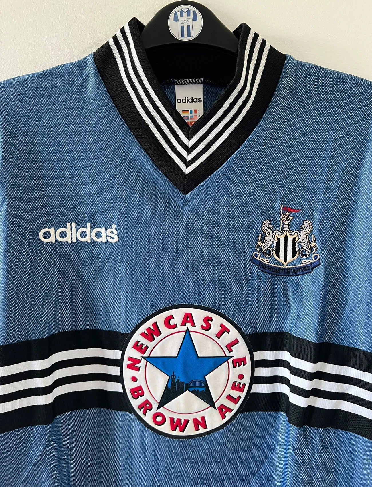 Maillot de foot vintage extérieur bleu de Newcastle de la saison 1996/1997. On peut retrouver l'équipementier Adidas et le sponsor Newcastle Brown Ale. Il s'agit d'un maillot authentique d'époque.