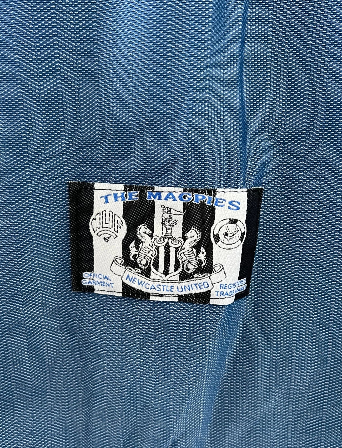 Maillot de foot vintage extérieur bleu de Newcastle de la saison 1996/1997. On peut retrouver l'équipementier Adidas et le sponsor Newcastle Brown Ale. Il s'agit d'un maillot authentique d'époque.