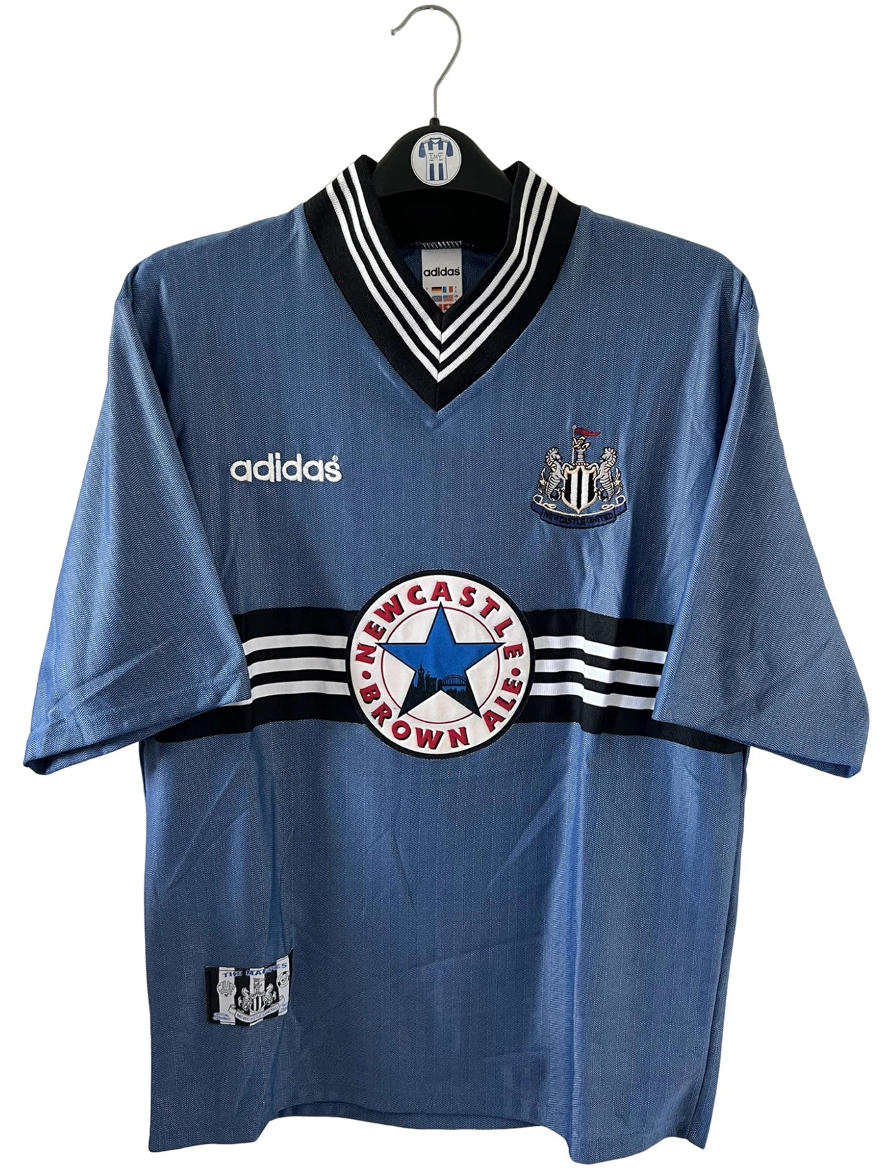 Maillot de foot vintage extérieur bleu de Newcastle de la saison 1996/1997. On peut retrouver l'équipementier Adidas et le sponsor Newcastle Brown Ale. Il s'agit d'un maillot authentique d'époque.