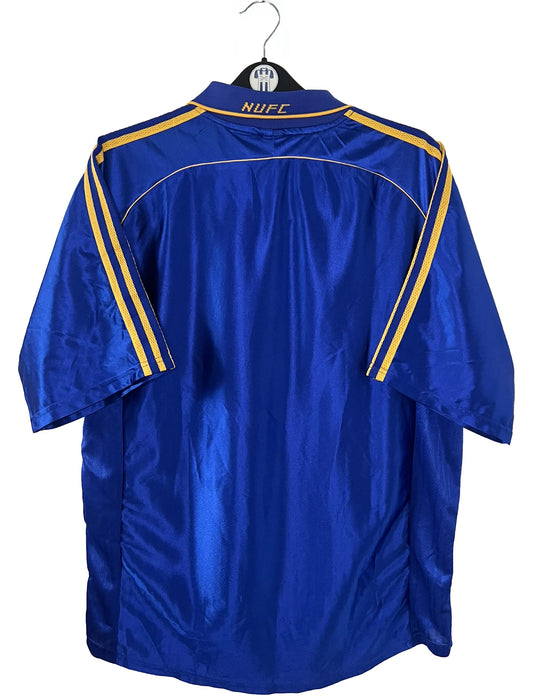 Maillot de foot vintage extérieur bleu de Newcastle de la saison 1998/1999. On peut retrouver l'équipementier Adidas et le sponsor Newcastle Brown Ale. Il s'agit d'un maillot authentique d'époque.