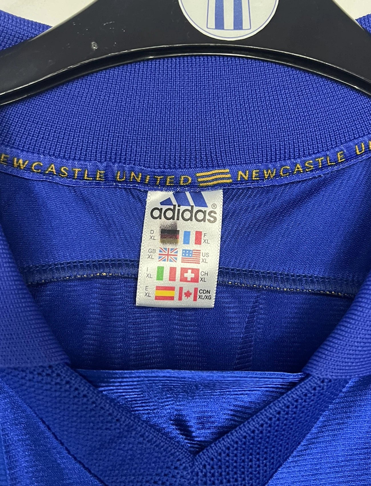 Maillot de foot vintage extérieur bleu de Newcastle de la saison 1998/1999. On peut retrouver l'équipementier Adidas et le sponsor Newcastle Brown Ale. Il s'agit d'un maillot authentique d'époque.