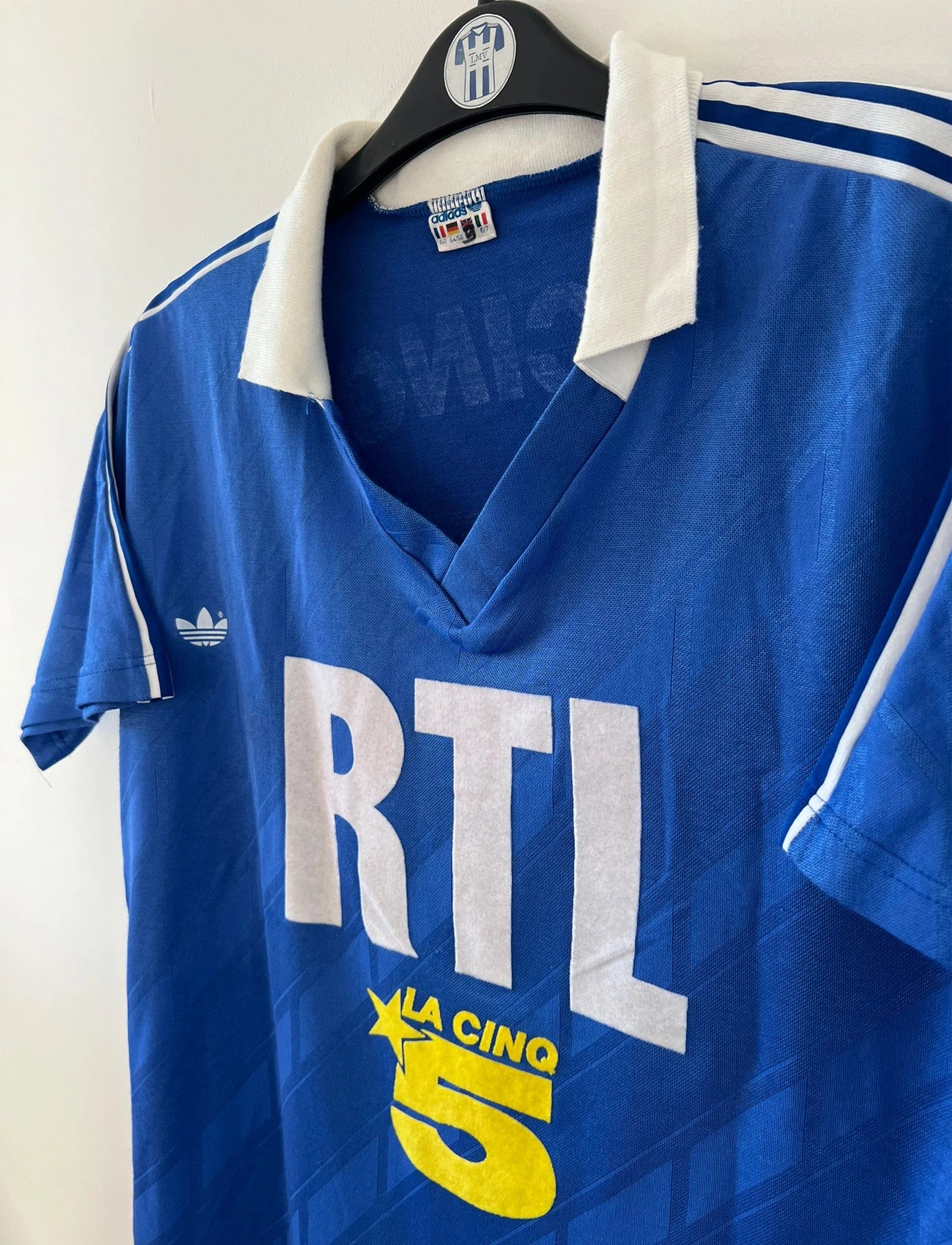 Maillot de foot vintage extérieur bleu du PSG saison 1988/1989. On peut retrouver l'équipementier Adidas et le sponsor RTL, La Cinq et Canal +. Il s'agit d'un maillot authentique d'époque.