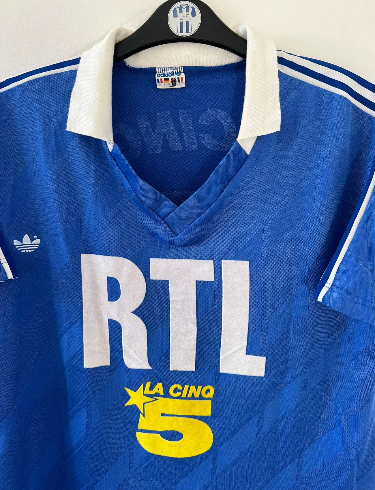 Maillot de foot vintage extérieur bleu du PSG saison 1988/1989. On peut retrouver l'équipementier Adidas et le sponsor RTL, La Cinq et Canal +. Il s'agit d'un maillot authentique d'époque.