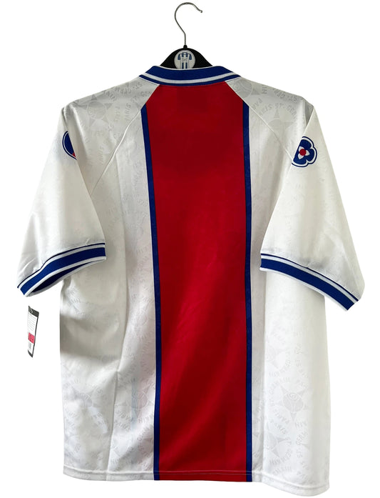 Maillot de foot vintage extérieur blanc avec un bande rouge du PSG de la saison 1994/1995. On peut retrouver l'équipementier Nike. Il s'agit d'un maillot issu du stock pro du PSG avec son étiquette d'époque. Il s'agit d'un maillot authentique.